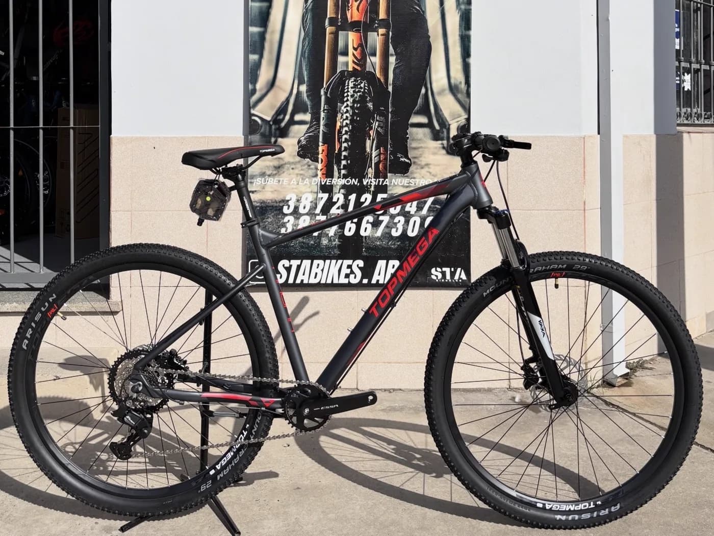 Bicicleta Topmega Magma negra apoyada frente al local de STA BIKES