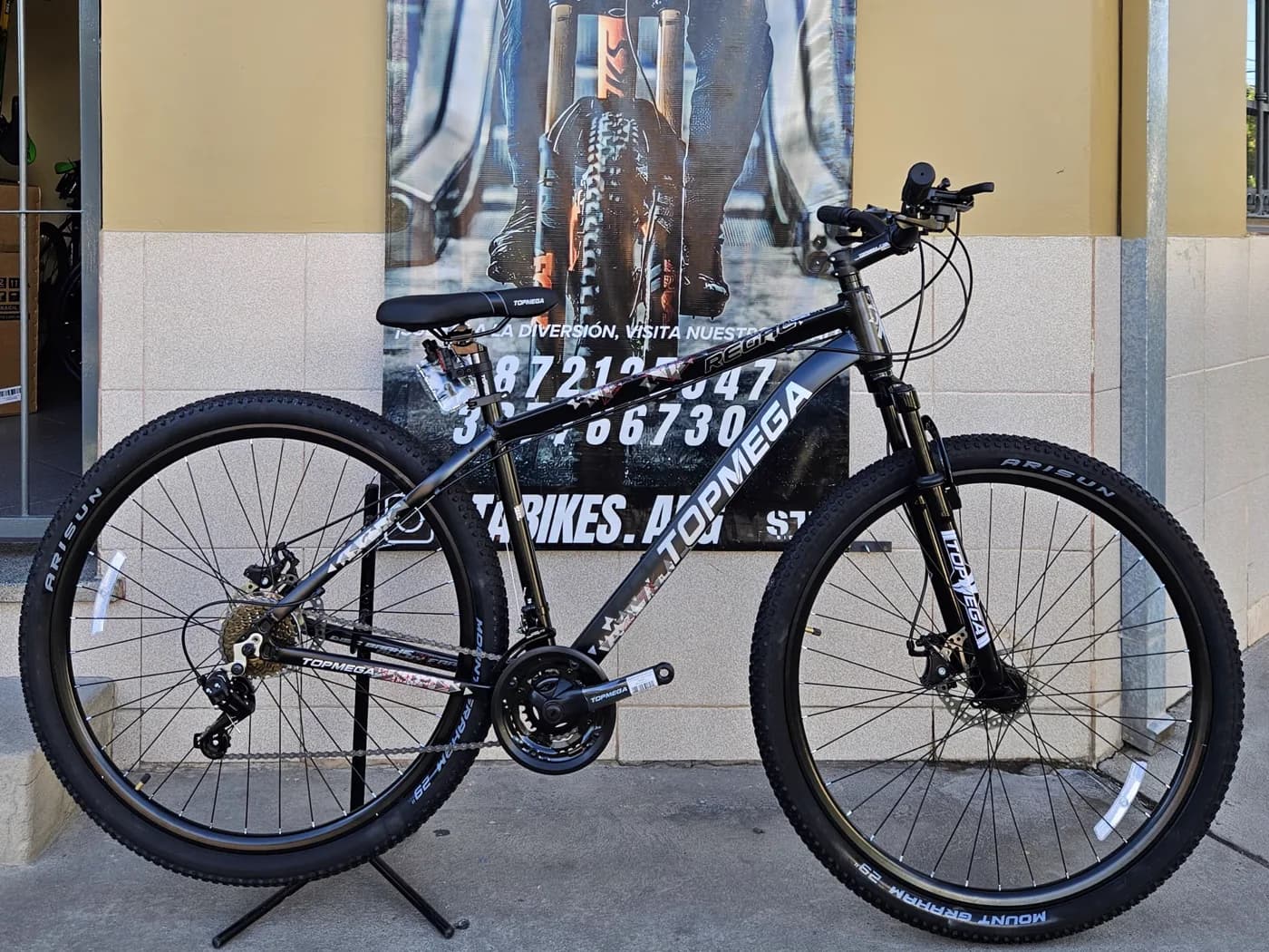 Bicicleta Topmega Regal negra apoyada frente al local de STA BIKES