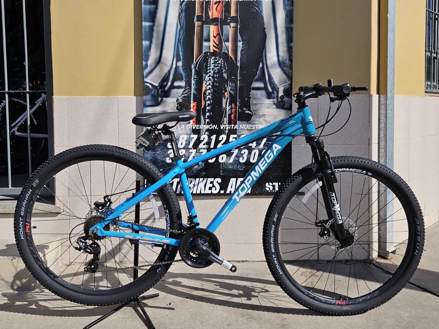 Bicicleta Topmega Sunshine celeste apoyada frente al local de STA BIKES