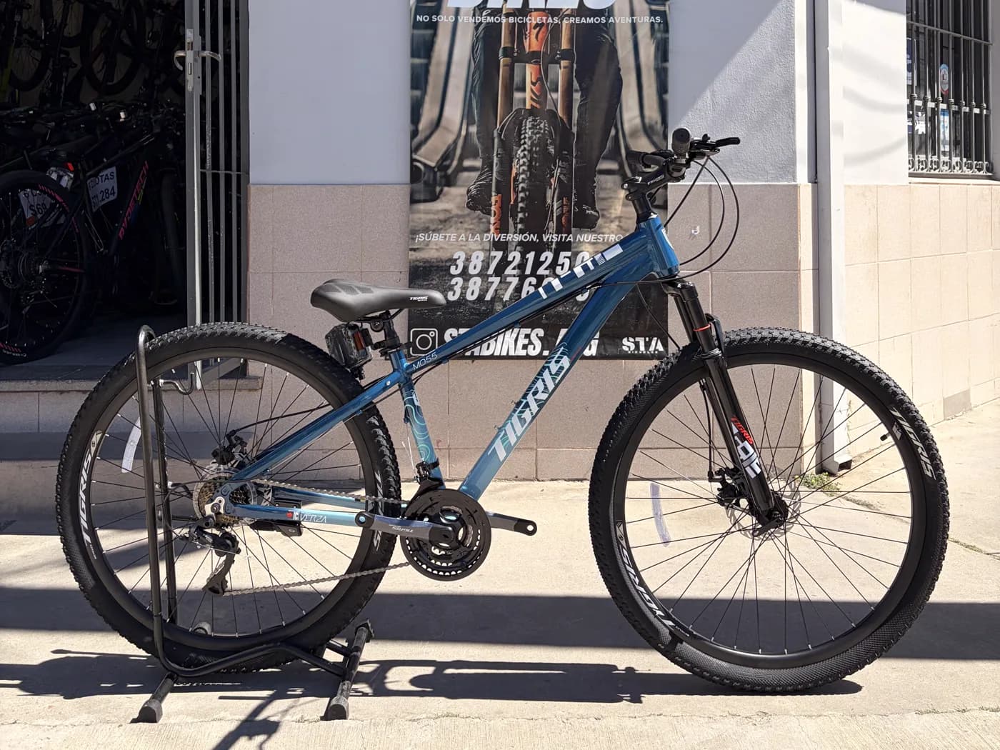 Bicicleta Topmega Tigris celeste apoyada frente al local de STA BIKES